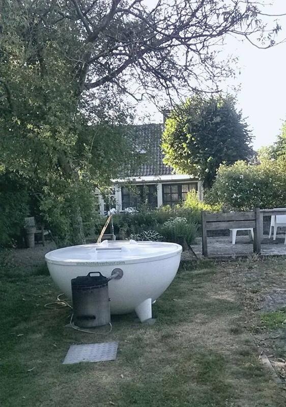 Witte Dutchtub met houtkachel in een tuin bij een woning